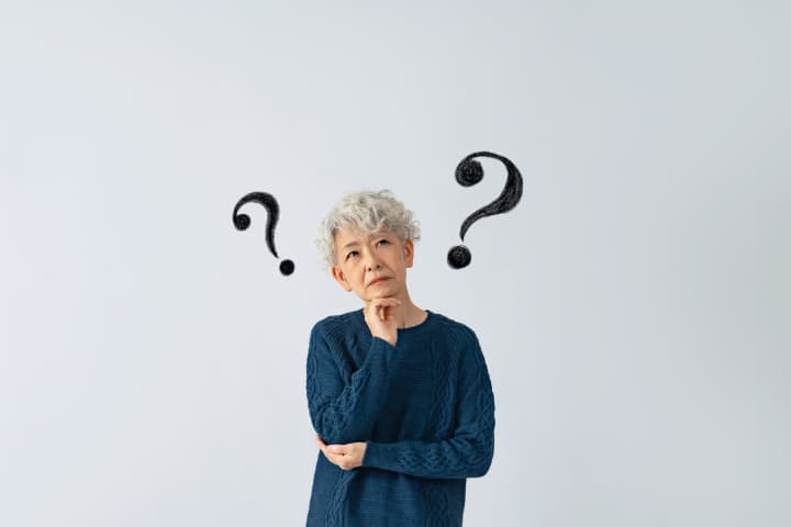 入れ歯が外れる原因を考える女性